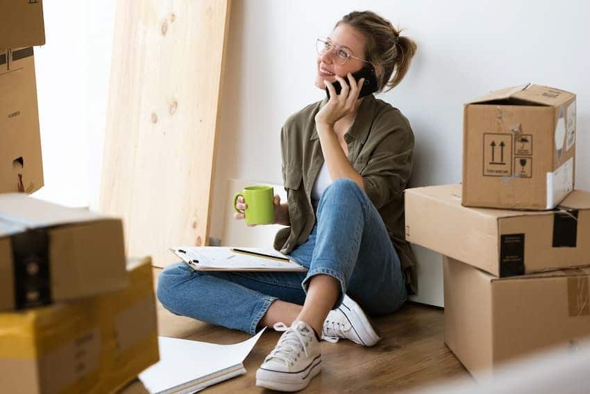 in kleinere Wohnung umziehen: Frau sitzt auf gepackten Kartons