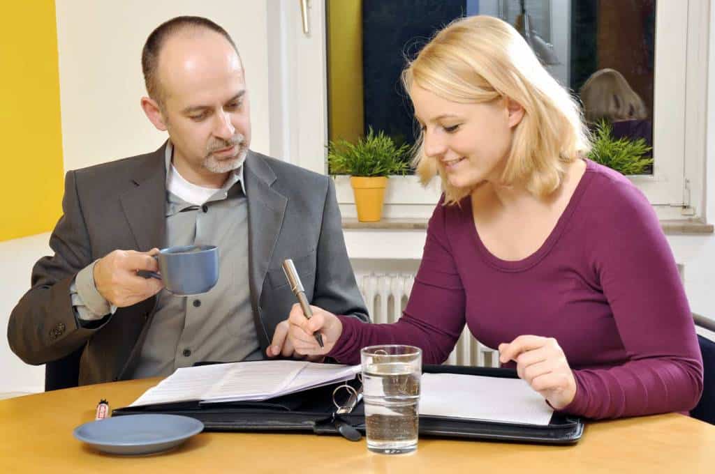 zwei Anleger sehen sich Unterlagen zu einer vermieteten Wohnung als Kapitalanlage an