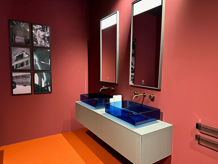 neues fürs Bad: Bild zeigt den Showroom von Artelinea mit zwei identischen Waschtischen aus rechteckigen transparenten blauen Material an rotbrauner Wand