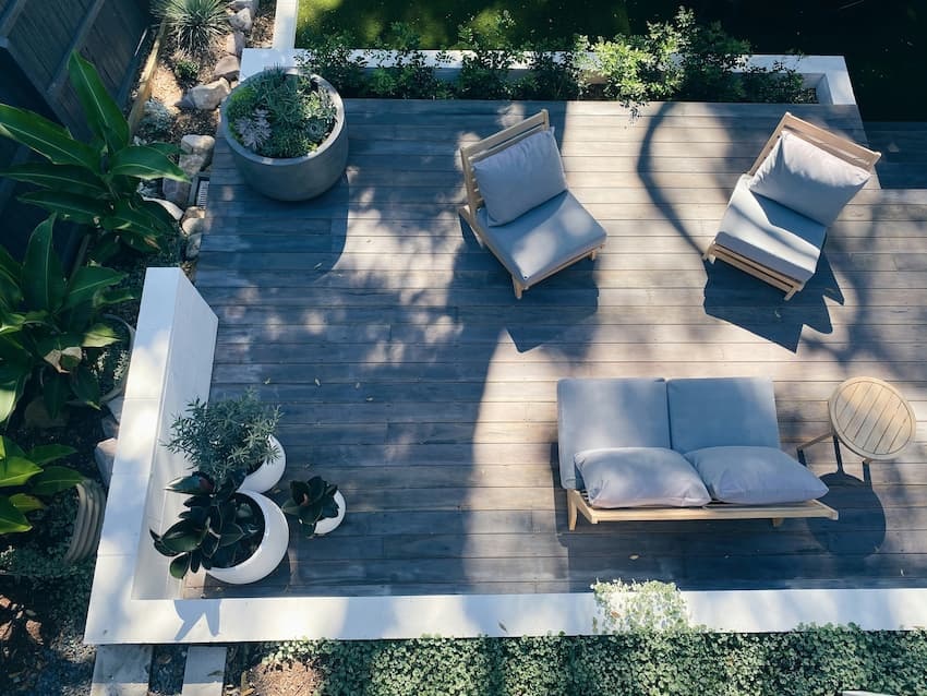 gemütliche Terrasse: Bild zeigt Holzterrasse von oben, darauf Blumenkübel und eine Outdoor-Sitzgruppe