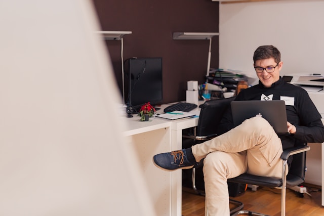 Wege aus der Schuldenfalle: Bild zeigt lachenden Mann am Schreibtisch mit Laptop 