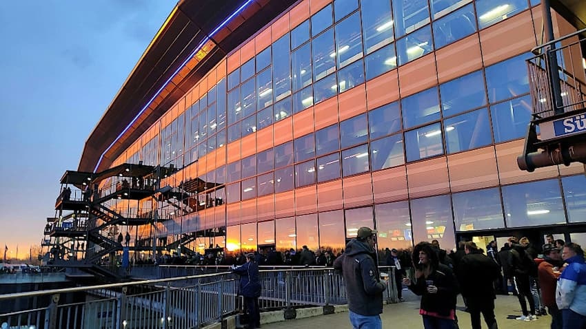 Bild zeigt Arena in Gelsenkirchen von außen mit zahlreichen Besuchern am Abend bei Sonnenuntergang