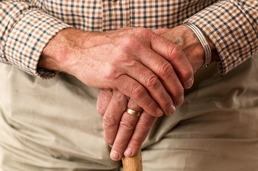 Rente mit Immobilie aufbessern: Bild zeigt Hände eines Rentners die einen Gehstock halten